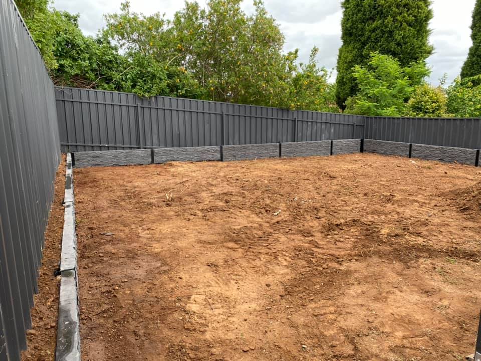 New grey metal fencing around a cleared dirt backyard with low sleeper edging