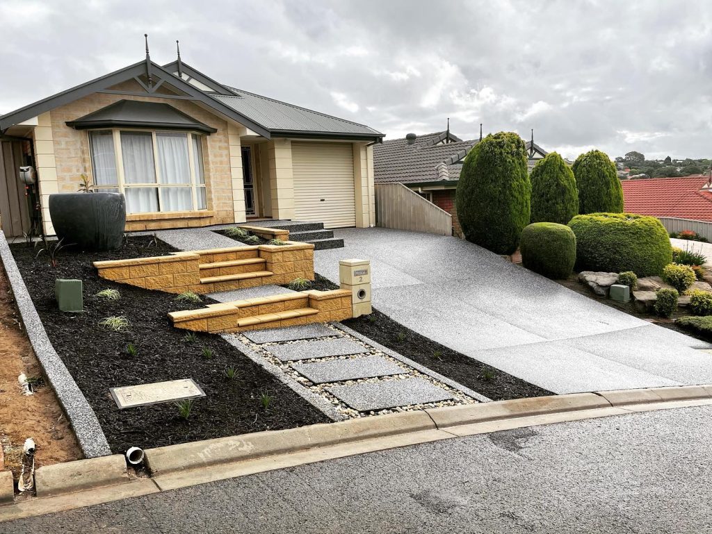 Front yard with a concrete driveway, block steps, stepping-stone path and black mulch beds