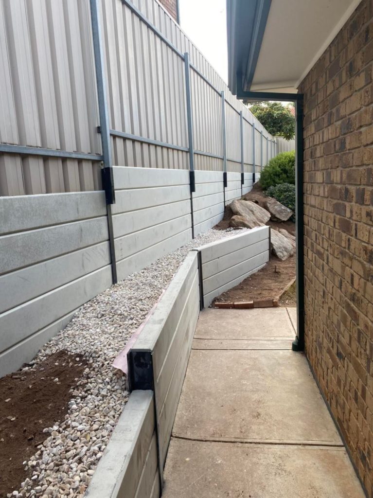 Concrete sleeper retaining wall with steel posts beside a narrow side path