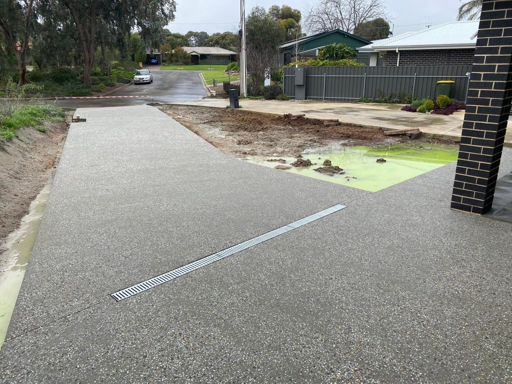 New exposed aggregate concrete driveway with a strip drain across it